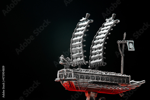 A small model of famous ancient Korean ironclad war ship. Korean turtle ship on a black background. Black and white and red.