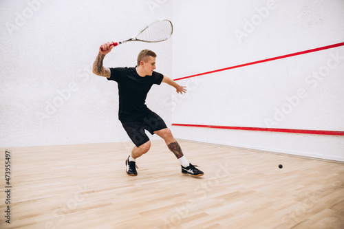 Foto Full-length portrait of young sportive man in black uniform training, playing sq