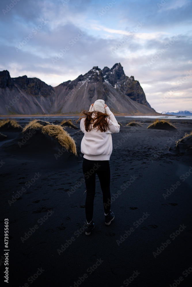 Fototapeta premium Young peaceful woman enjoying view of the moss covered meadows in Iceland. Arctic circle wild nature. People and nature connection. Traveling and camping