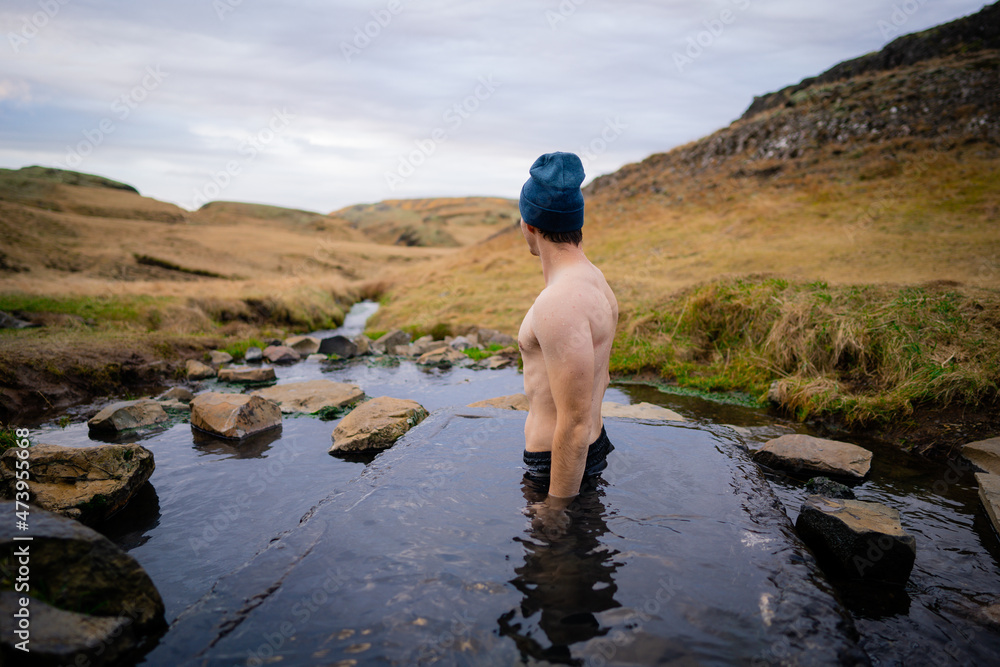 Man relaxing in a small geothermal hot spring pool in Hrunalaug, Iceland - obrazy, fototapety, plakaty 