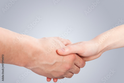 Two Hands Of caucasian Couple Connected Together Demonstrating Support and Encuragement of Two Loving People Over Gray Background