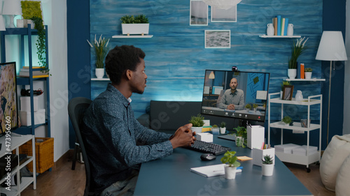 Remote black worker using internet web online communication to talk with his boss while working from home. African american guy on video call using wireless technology for connection and communication