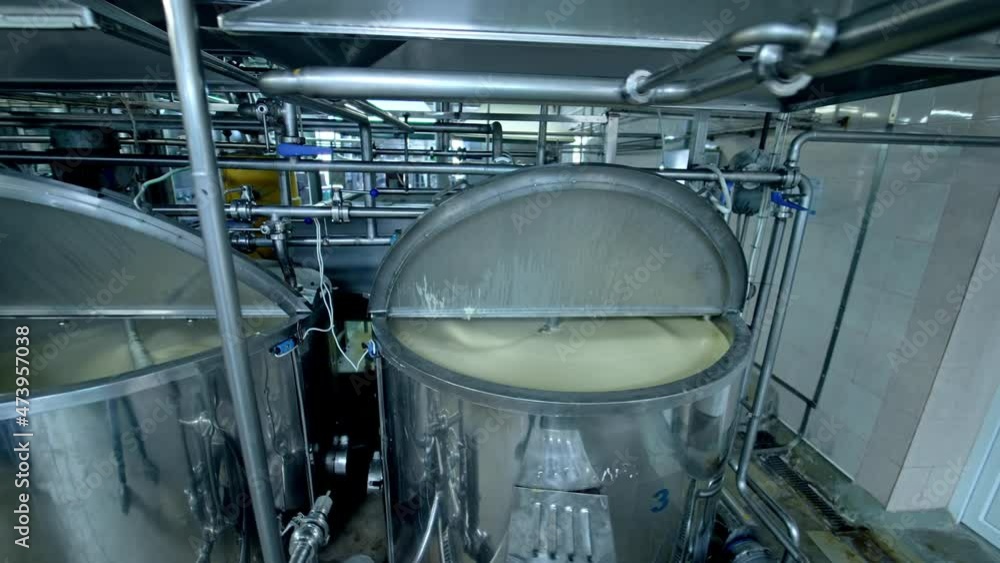 Three silver tanks for mixing milk products. Dairy production at the modern food factory. Steel tanks with open lids standing in row. Three silver tanks for mixing milk products. Dairy production at the modern food factory. Steel tanks with open lids standing in row.