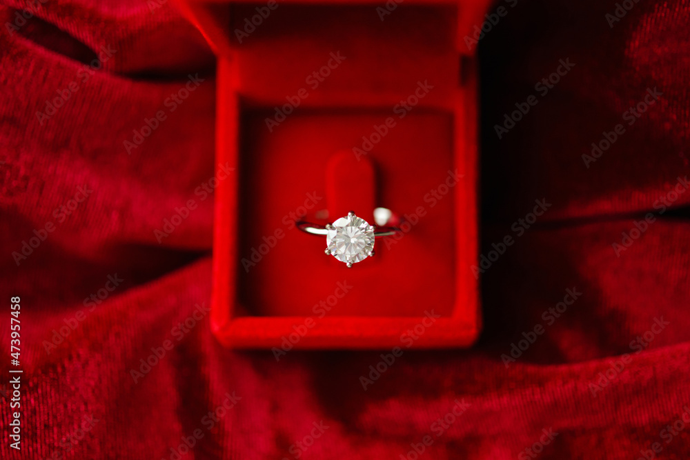 Diamond ring in jewelry gift box on red fabric background Diamond ring in jewelry gift box on red fabric background