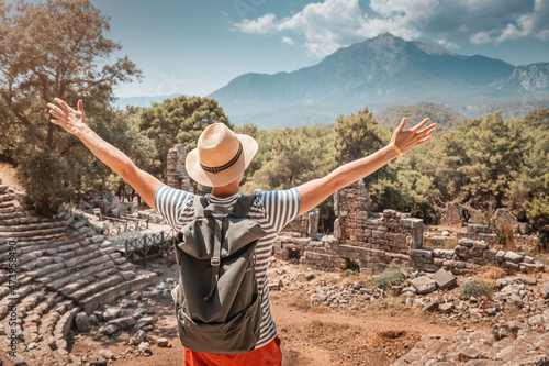 Male traveler explores the ruins of an ancient amphitheatre in antique Greek city. Wanderlust and backpacking concept photo