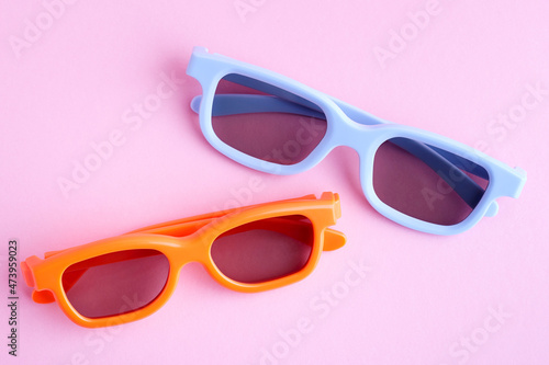 Blue and orange 3D glasses on a pink background. View from above
