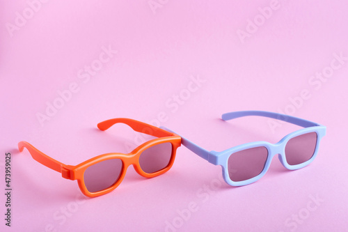 Blue and orange 3D glasses on a pink background. Front-top view. 