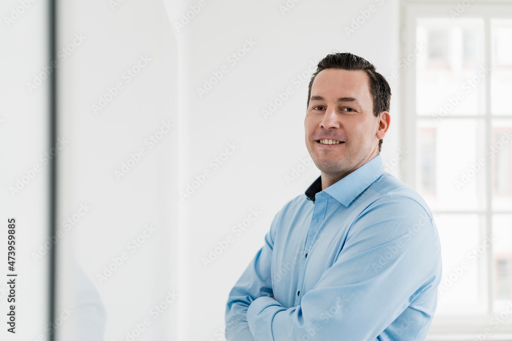 Smiling businessman standing with arms crossed at office Smiling businessman standing with arms crossed at office