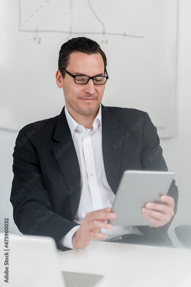 Male entrepreneur sitting and using digital tablet at workplace Male entrepreneur sitting and using digital tablet at workplace