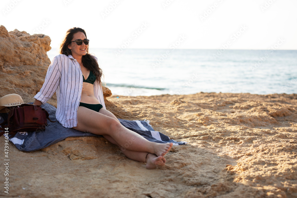 Happy young woman relaxing on the sandy beach. Beautiful woman enjoying a summer day on the beach..