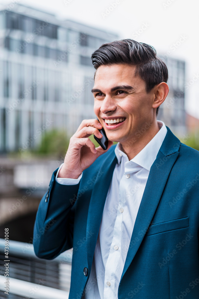 Smiling male professional looking away while talking on smart phone Smiling male professional looking away while talking on smart phone