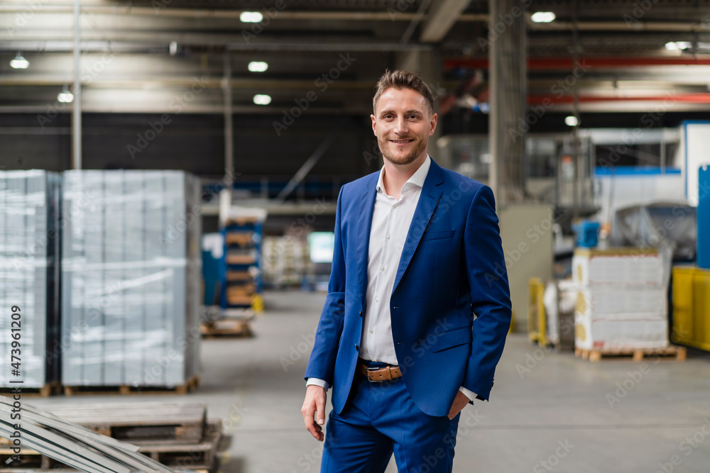 Smiling businessman with hand in pocket standing at industry Smiling businessman with hand in pocket standing at industry