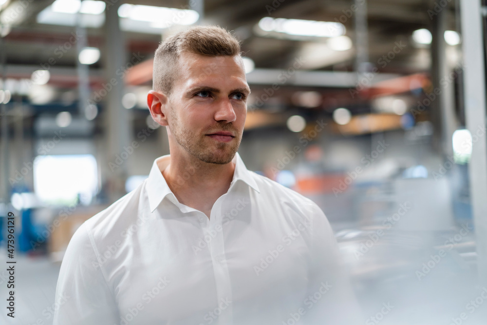 Thoughtful young businessman looking away in industry Thoughtful young businessman looking away in industry