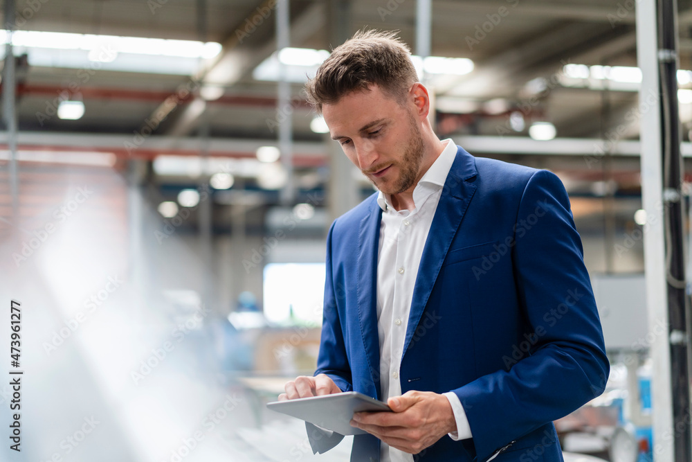 Male professional in blue blazer using digital tablet in factory Male professional in blue blazer using digital tablet in factory