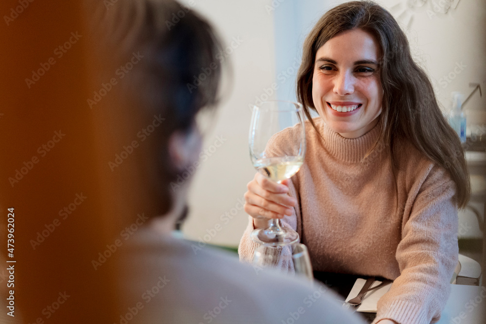 Smiling woman with wine glass looking at boyfriend in restaurant Smiling woman with wine glass looking at boyfriend in restaurant