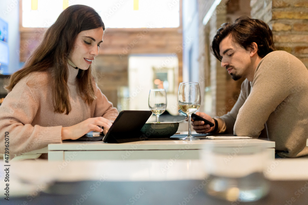 Young couple using wireless technology at restaurant table Young couple using wireless technology at restaurant table