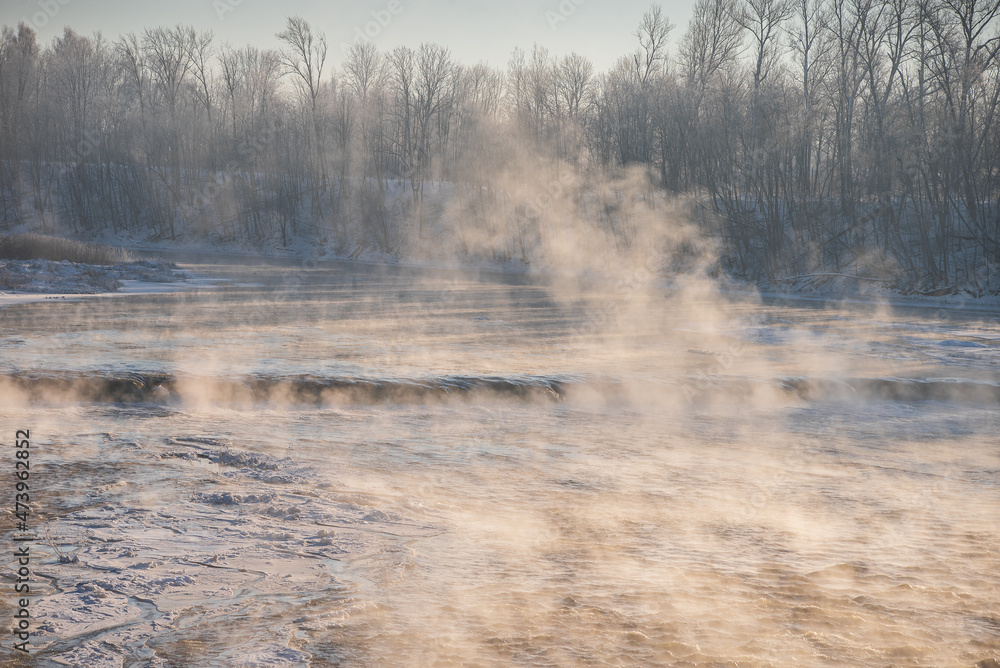 Obraz premium Venta river waterfall in the fog in cold, sunny winter morning, Kuldiga, Latvia