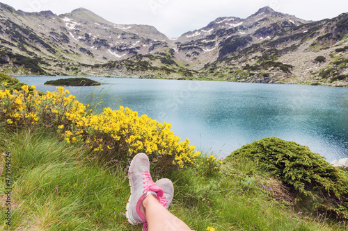 Legs of hiker woman traveler relaxing on a field with lake in Pirin mountain .Mountain tourism concept photo
