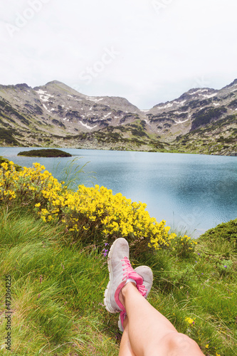 Legs of hiker woman traveler relaxing on a field with lake in Pirin mountain .Mountain tourism concept photo