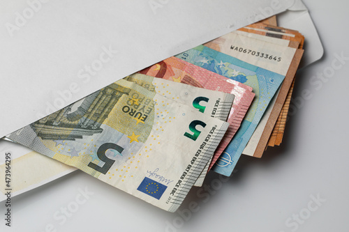 Closeup with envelope full of Euro banknotes on white background