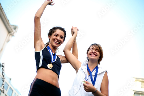 Happy female athles wearing medals celebrating success photo