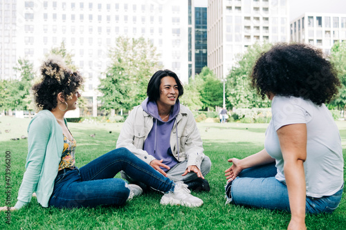 Young man talking to multi ethnic female friends at park photo