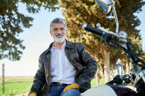 Smiling man wearing biker Jacket sitting on motorcycle