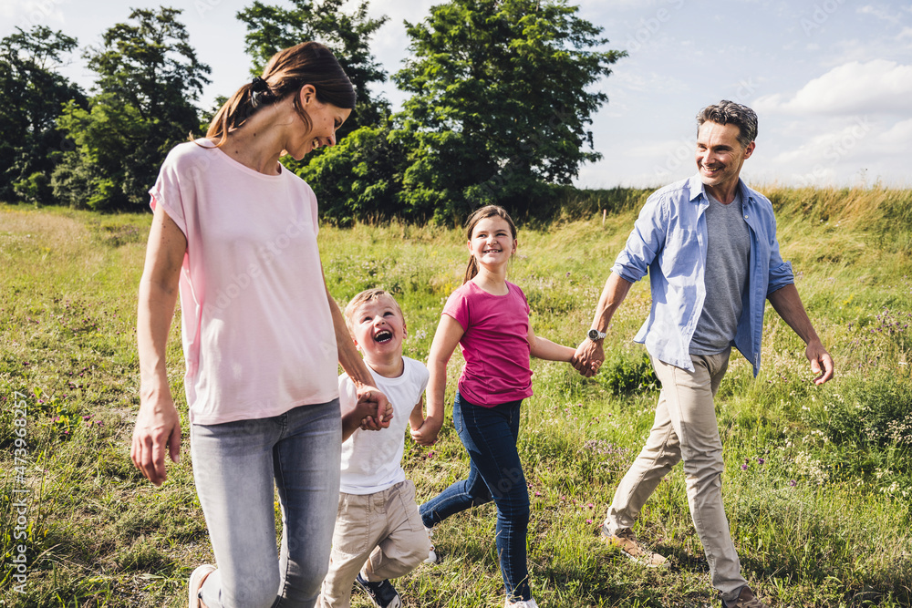 Children holding hands of parents while walking at meadow Children holding hands of parents while walking at meadow