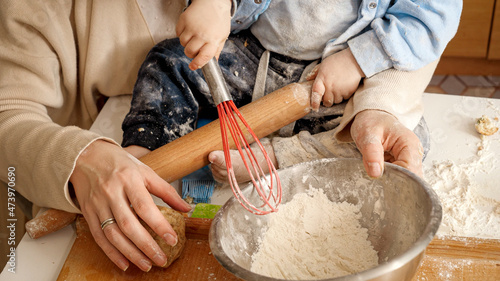 Принти на полотні Closeup of little baby boy kneading dough and flour in bowl for making bread with mother
