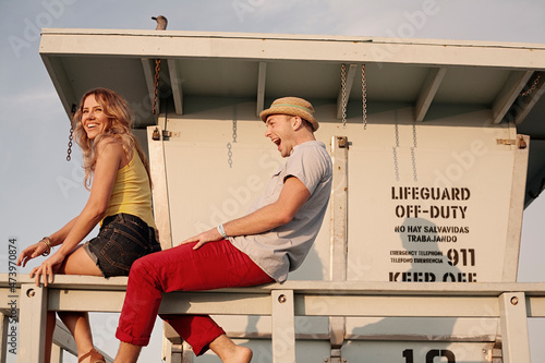 Beautiful woman sitting with boyfriend on railing at Santa Monica photo