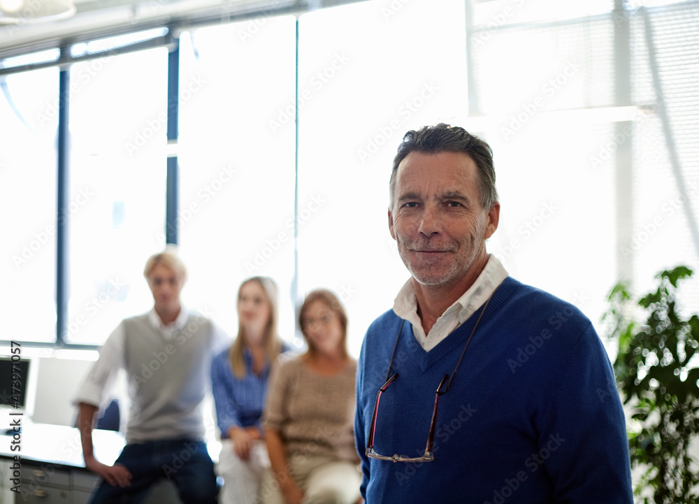 Smiling male entrepreneur with team of colleagues in background at office Smiling male entrepreneur with team of colleagues in background at office