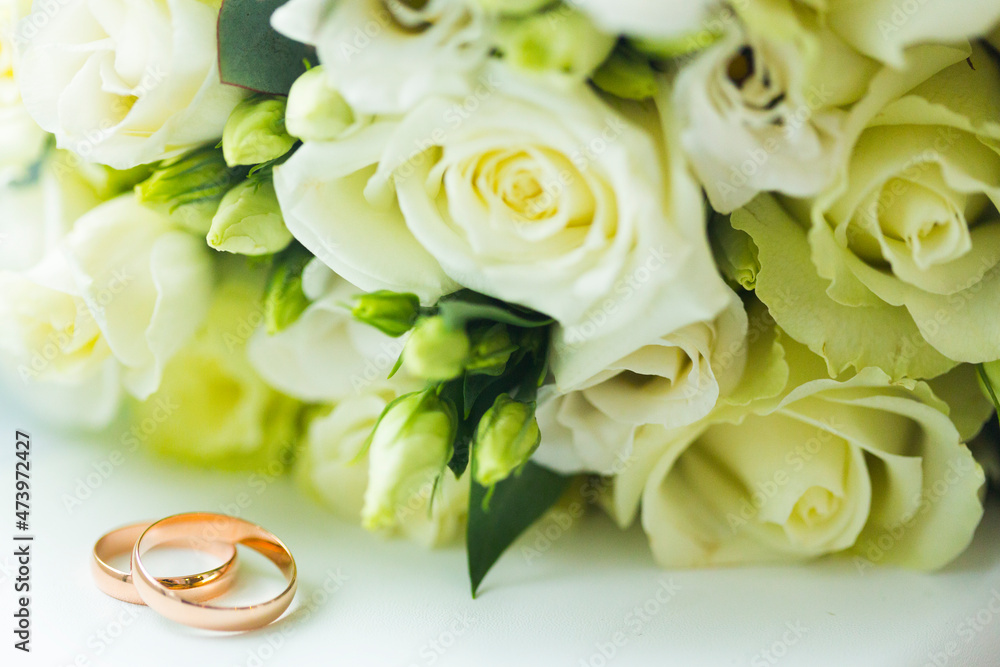 Golden wedding rings and wedding bouquet of pale yellow roses Golden wedding rings and wedding bouquet of pale yellow roses