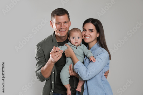 Happy family. Couple with their cute baby on grey background