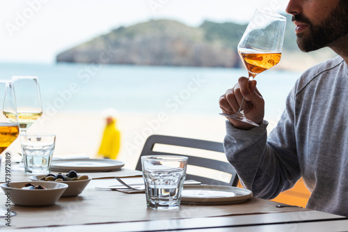 Young man drinking wine at beach restaurant