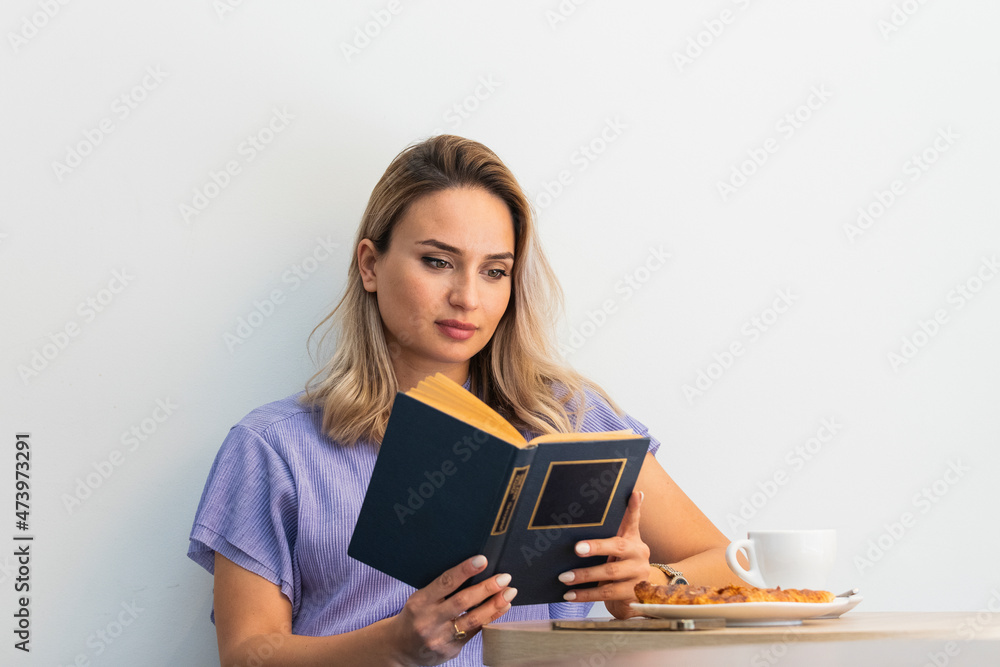 Beautiful woman reading book in front of wall at coffee shop Beautiful woman reading book in front of wall at coffee shop