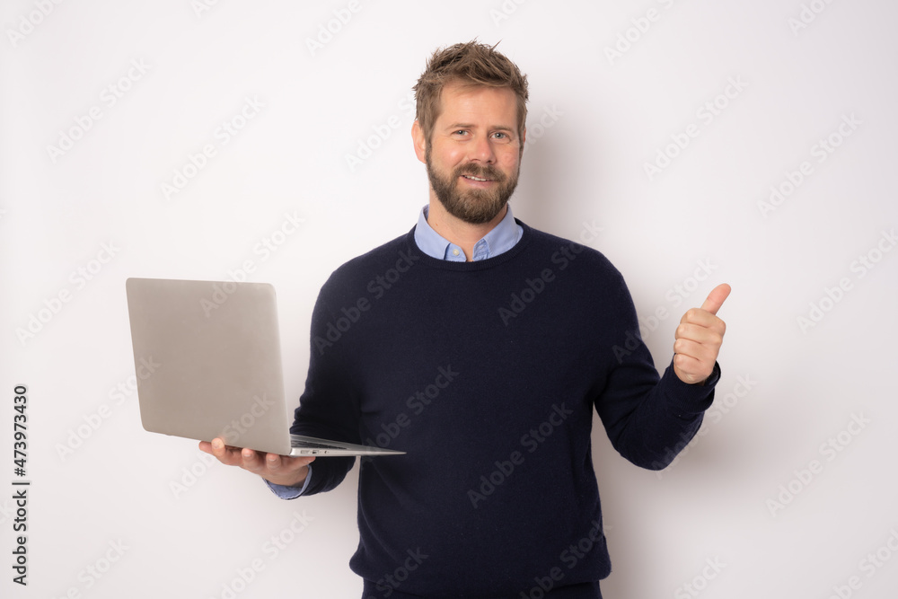 Young smiling handsome man holding laptop computer with thumb up standing isolated over white background. Young smiling handsome man holding laptop computer with thumb up standing isolated over white background.