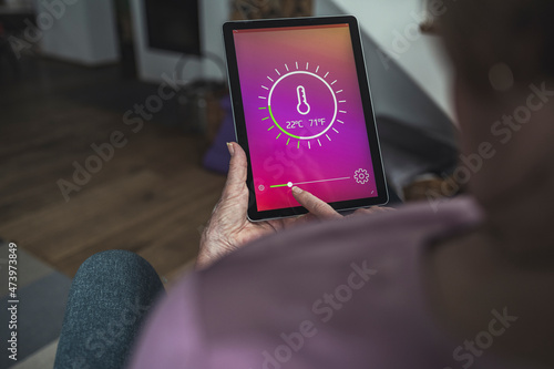 Woman controlling room temperature through digital tablet at home photo