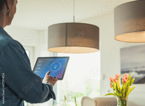 Woman operating lighting equipment through digital tablet at home