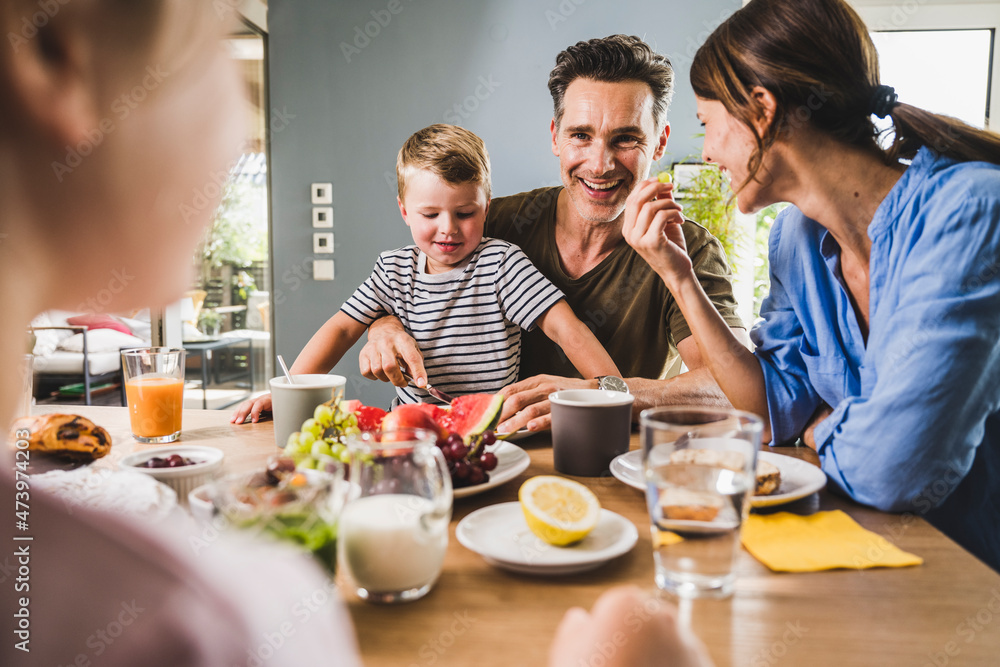 Happy family eating fruits during breakfast at home Happy family eating fruits during breakfast at home