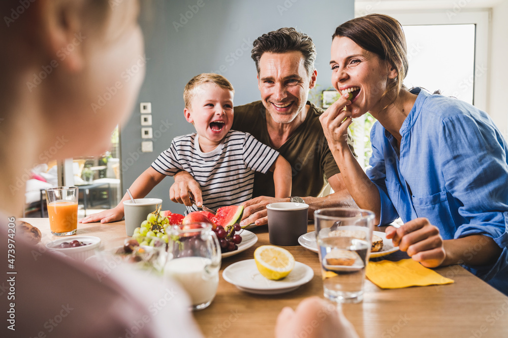 Father and mother looking at daughter while having breakfast at home Father and mother looking at daughter while having breakfast at home
