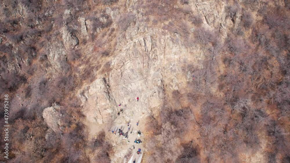 Rock climbing training on a steep slope in the mountains. The view from the drone. A group of people climb to the top of cliff. Brave girls and boys are looking for a trail on a cliff. Extreme sports Rock climbing training on a steep slope in the mountains. The view from the drone. A group of people climb to the top of cliff. Brave girls and boys are looking for a trail on a cliff. Extreme sports