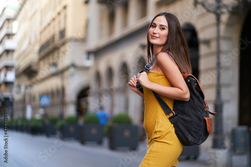 pretty young woman crossing a street, with her backpack on her back