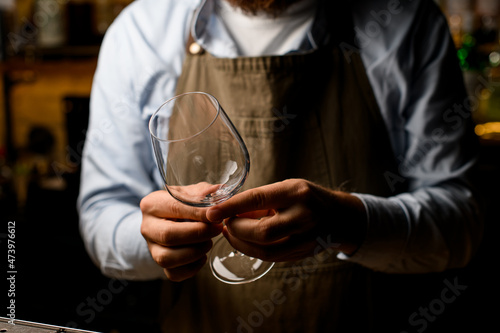 selective focus of male bartender hands neatly holding an empty wine goblet glass.