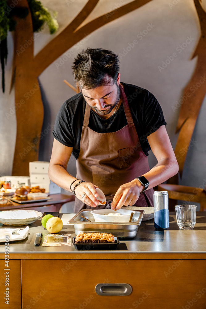 Mature chef garnishing food while standing in modern restaurant kitchen Mature chef garnishing food while standing in modern restaurant kitchen
