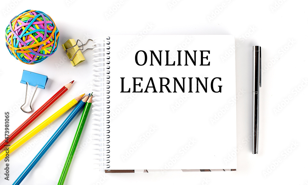 Notebook ,pencils,pen and rubber band with text ONLINE LEARNING on the white background Notebook ,pencils,pen and rubber band with text ONLINE LEARNING on the white background