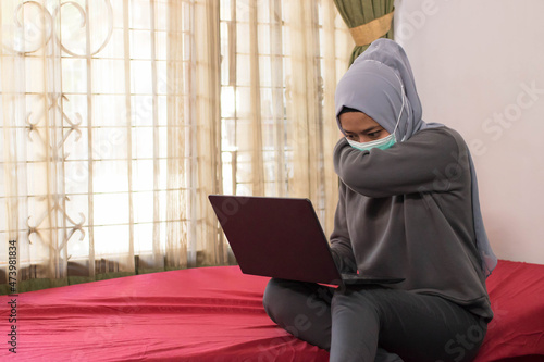 Asian women in hijabs with masks are coughing when working from home © rineca