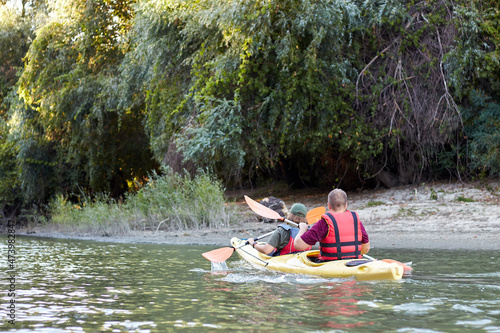 Back view of happy young couple kayaking on small river together. Having fun in leisure activity. Romantic and happy woman and man on the kayak. Sport, relations concept.