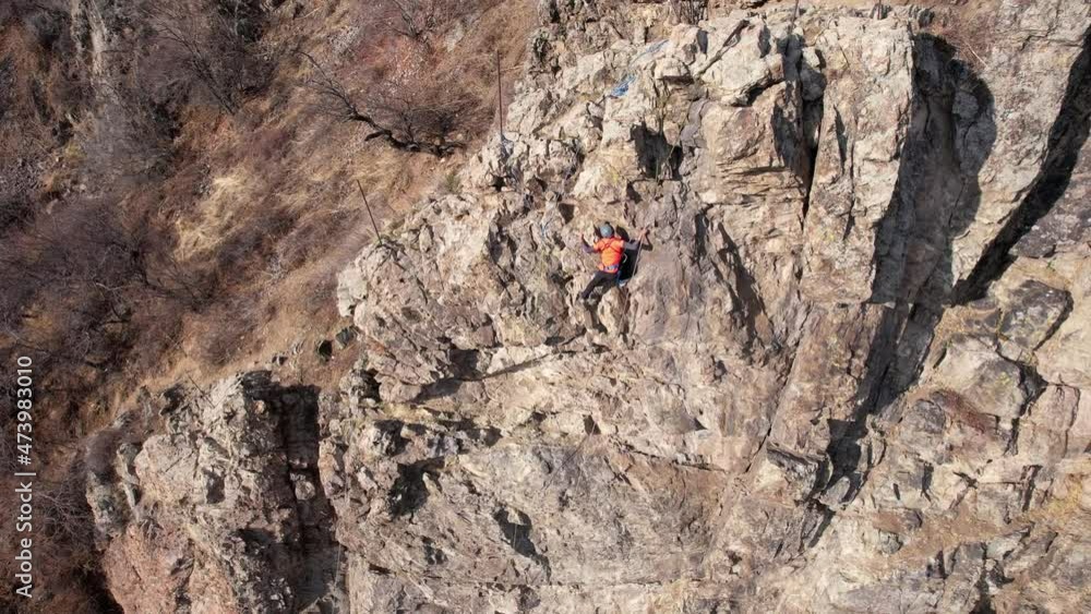 Rock climbing training on a steep slope in the mountains. The view from the drone. A group of people climb to the top of cliff. Brave girls and boys are looking for a trail on a cliff. Extreme sports Rock climbing training on a steep slope in the mountains. The view from the drone. A group of people climb to the top of cliff. Brave girls and boys are looking for a trail on a cliff. Extreme sports