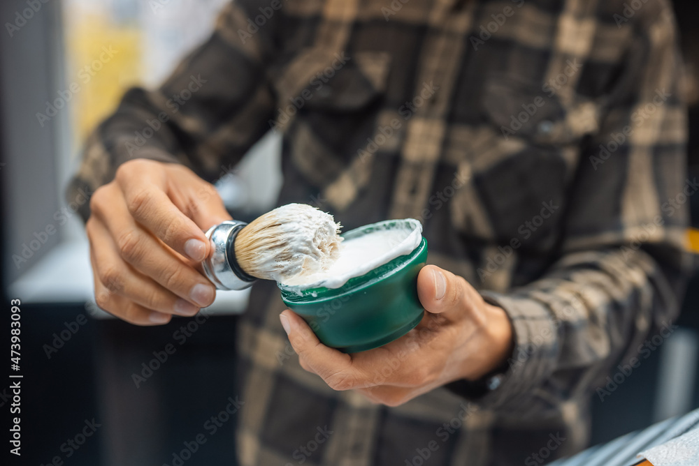 The master holds a brush and shaving foam in his hand The master holds a brush and shaving foam in his hand