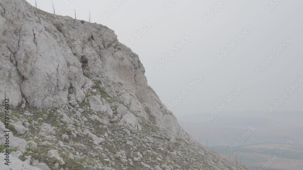 Hiker climbing mountainside in thick smoke Hiker climbing mountainside in thick smoke